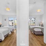 Zwei Schlafzimmer mit Betten, Holzboden und Fenstern zum Außenbereich.