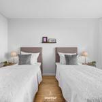 Zwei Schlafzimmer mit weißen Bettwäschen und Holzboden.