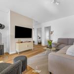 Wohnzimmer mit Kamin, Sofa und Fernseher. Holzboden und moderne Einrichtung.