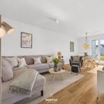 Wohnzimmer mit Sofa, Couchtisch und Fernseher. Esstisch mit Stühlen und Fensterblick.
