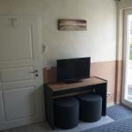 Zimmer mit TV, Stühlen und Balkontür. Wandbild und Tür sichtbar.