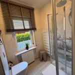 Bad mit Dusche, Toilette und Fenster mit Jalousie.