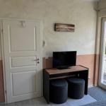 Schlafzimmer mit TV-Tisch, zwei Sitzkissen und Balkontür.