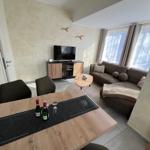 Wohn- und Essbereich mit Sofa, TV und Tisch mit Flaschen.