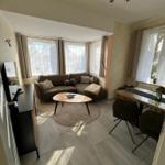 Wohn- und Essbereich mit Sofa, Esstisch und Fenstern.