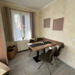 Esszimmer mit Tisch, Stühlen und Fenster. Wanddekoration und Bodenfliesen.