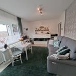 Wohn- und Essbereich mit Sofa, Tisch und Fenster.