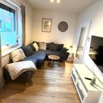 Wohnzimmer mit Ecksofa, Holzboden und Fernseher