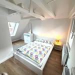 Schlafzimmer mit Dachschräge, Bett, Nachttisch und Fenster