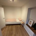 Schlafzimmer mit Bett, Nachttisch und Holzboden.