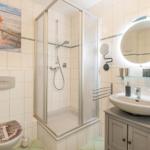 Badezimmer mit Dusche, Waschbecken und Toilette. Wandbild mit Hund.
