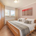 Schlafzimmer mit Holzbett, Kleiderschrank und Fenster mit Blick.