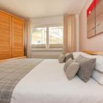 Schlafzimmer mit Bett, Kleiderschrank und Fenster zum Balkon.