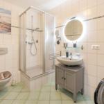 Badezimmer mit Dusche, Waschbecken und Waschmaschine.