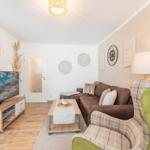 Wohnzimmer mit Sofa, Sessel, Fernseher und Tisch.