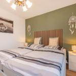 Schlafzimmer mit Doppelbett, grüner Wand und Nachttischen