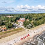 Strand mit Strandkörben, Wald und Hotels am Wasser