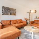 Wohnzimmer mit braunen Ledersofas, runden Tisch und Wandbild mit Zebra-Muster.