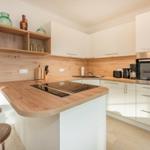 Moderne Küche mit Holz Arbeitsfläche und weißen Schränken. Einbauherd und Backofen sind vorhanden.