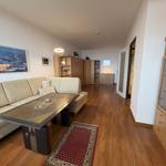 Wohnzimmer mit Sofa, Tisch und Holzboden. Regal und Schrank sind sichtbar.