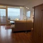 Wohnzimmer mit Sofa, Bodenbelag und Balkon mit Meerblick.