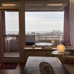 Wohnraum mit Blick auf das Meer und Balkon mit Tisch und Stühlen.