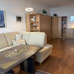 Wohnzimmer mit Sofa, Tisch und Holzmöbeln. Wandbild und Beleuchtung sichtbar.