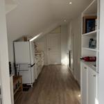 Küche mit Kühlschrank und Holzboden. Regal mit Büchern und Feuerlöscher.