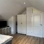 Schlafzimmer mit Dachschräge, Bett, Kleiderschrank und TV-Bereich.