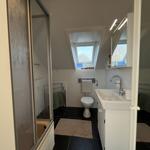 Badezimmer mit Dusche, Toilette und Waschbecken unter Dachschrägen