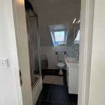 Badezimmer mit Dusche, Toilette und Waschbecken unter Dachschrägen.