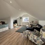 Schlafzimmer mit Bett und Wohnbereich mit Sofa und Sessel.