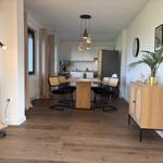 Essbereich mit Tisch, Stühlen und Küchenbereich im Hintergrund.