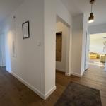 Flur mit Holzboden, Wandbild und Blick in Schlaf- und Wohnbereich.