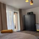 Schlafzimmer mit Bett, Kleiderschrank und Babybett. Fenster mit Vorhängen.