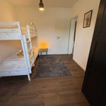 Zimmer mit Doppelstockbett, Teppich und Nachttisch mit Lampe.