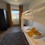 Zimmer mit Doppelstockbett, Fenster, Kleiderschrank und Teppich