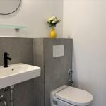 Badezimmer mit Waschbecken, Toilette und gelbem Vasenblumenarrangement.