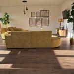 Wohnzimmer mit gelbem Sofa, Holzboden und Wandbildern.