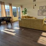 Wohnzimmer mit Sofa, Tischfußball und großen Fenstern.