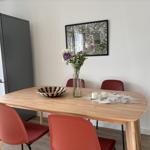 Essbereich mit Holztisch, roten Stühlen und Kühlschrank.