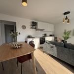 Wohnung mit Essbereich, Küche und Sofa. Holzboden und moderne Beleuchtung.