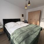 Schlafzimmer mit Doppelbett, Holzschrank und Nachttisch mit Lampe.
