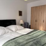 Schlafzimmer mit Bett, Kleiderschrank und Nachttischlampe.