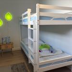 Zimmer mit Doppelstockbett, Nachttisch und Wandbeleuchtung in Blätterform.