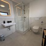 Badezimmer mit Dusche, Waschbecken und Toilette.