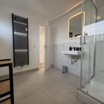 Badezimmer mit Dusche, Waschbecken und Heizkörper.