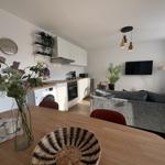 Wohnung mit Küche, Wohnzimmer und Esstisch. Dazu TV, Sofa und Pflanzen.