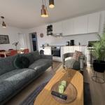 Wohnzimmer mit Sofa, Küchenzeile und Pflanze