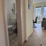 Flur mit Blick in Bad und Wohnzimmer mit Sofa und Fenster.